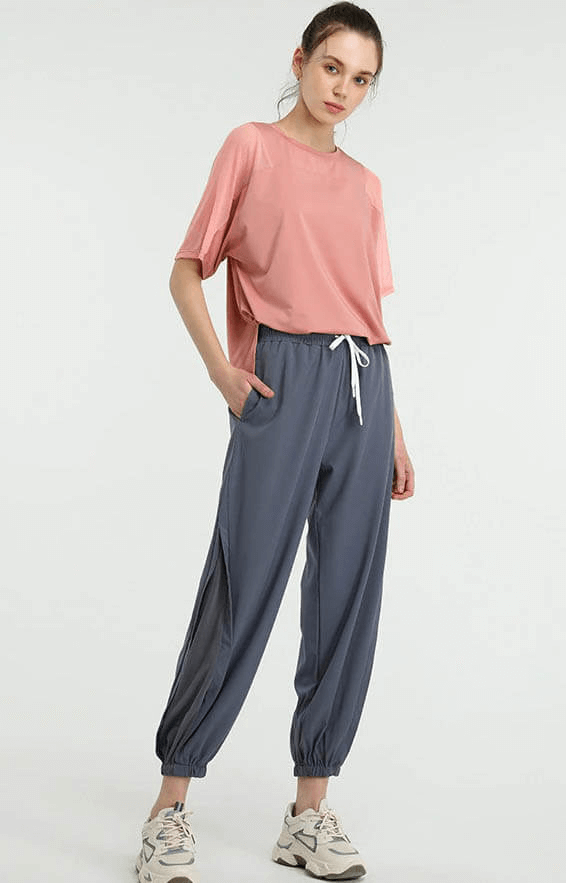 Woman in pink loose running mesh t-shirt and gray pants, perfect for workout or sports activities.